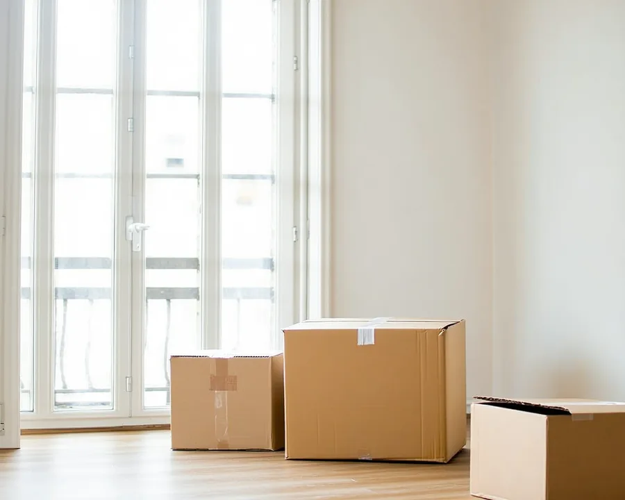 Bright UK flat interior with natural light, white walls, a small kitchen in background, welcoming and lived-in